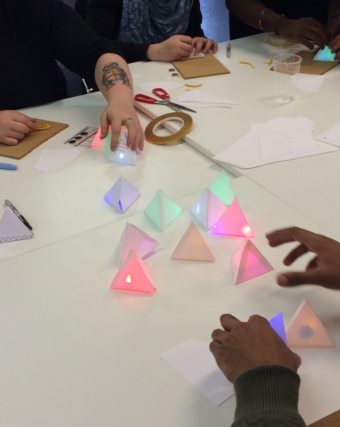 The group are placing their colourful light up paper pyramids in the centre of the table.