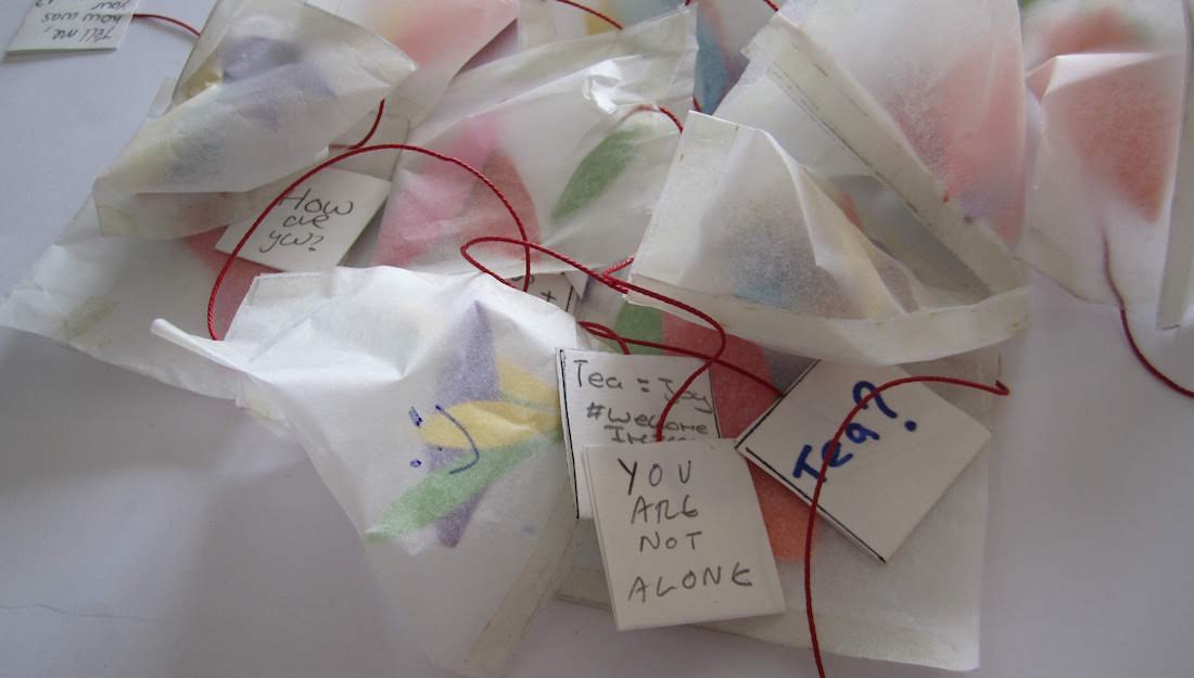 small pile of handmade teabags and labels that say 'how are you?', 'you are not alone', 'tea?'